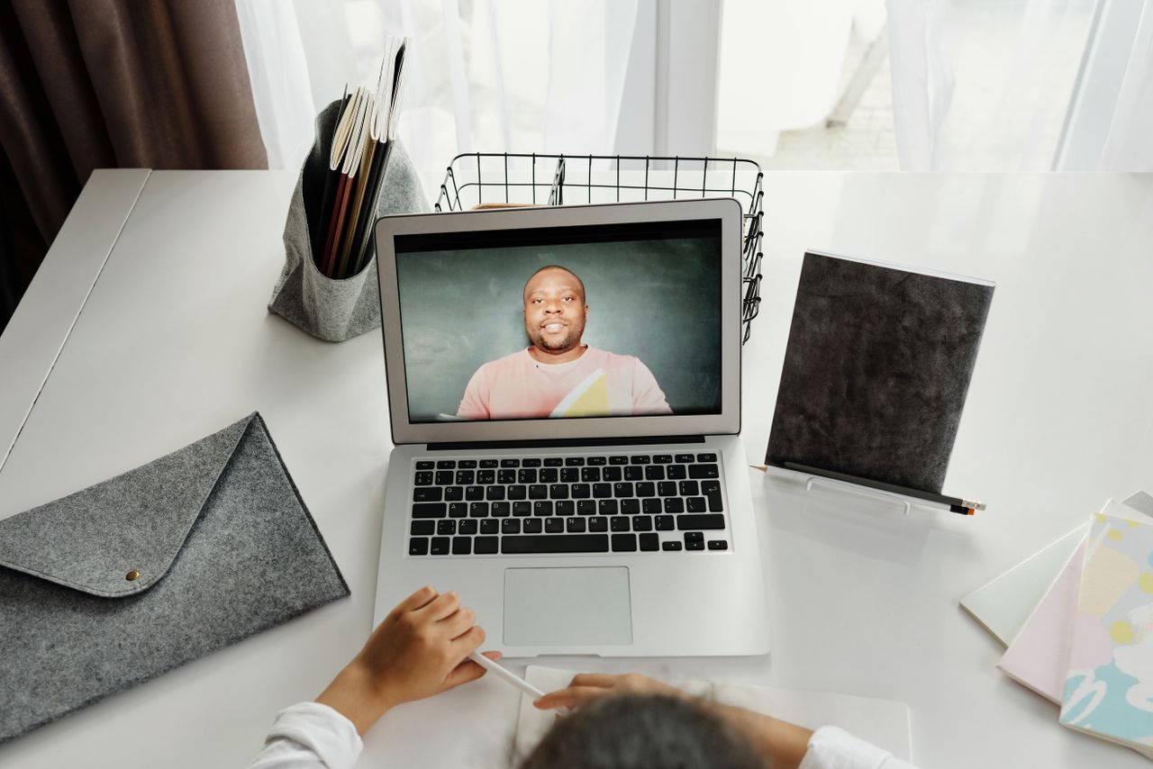 Services A student participates in a virtual class with a teacher on a laptop screen.